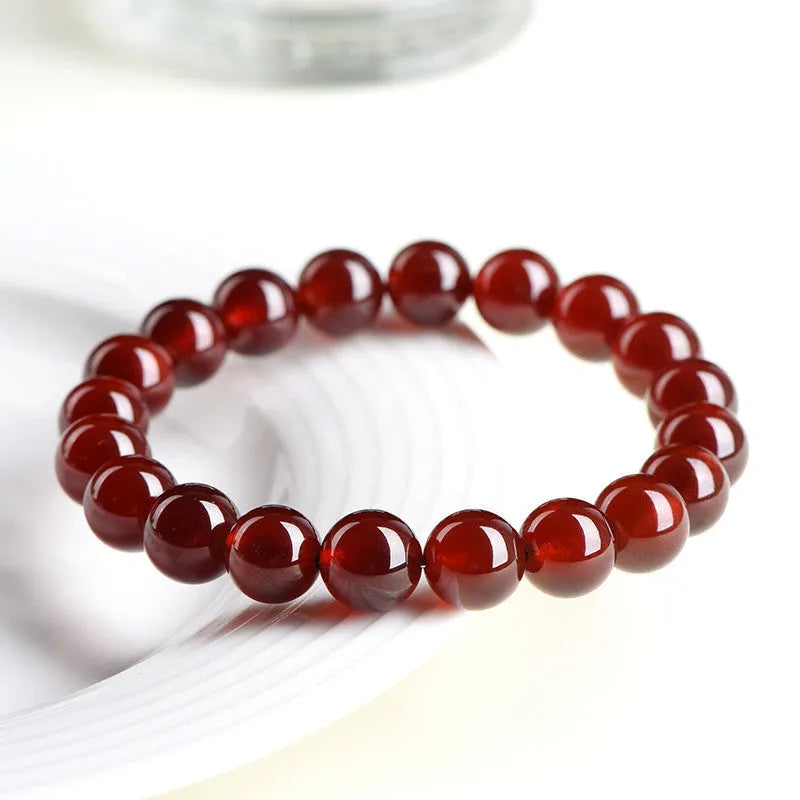 Natural orange red garnet ball bracelet in retro unisex style on wrist, showing crystal links and ruyi design details.