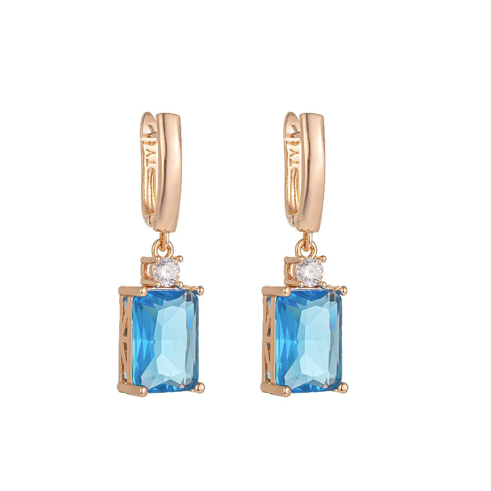 A pair of square-shaped gold-coloured electroplated earrings on a flat surface.