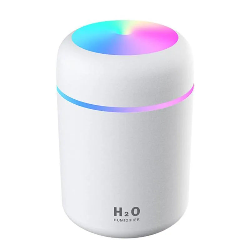 Pink USB desktop humidifier with LED lights and water tank on a wooden desk.