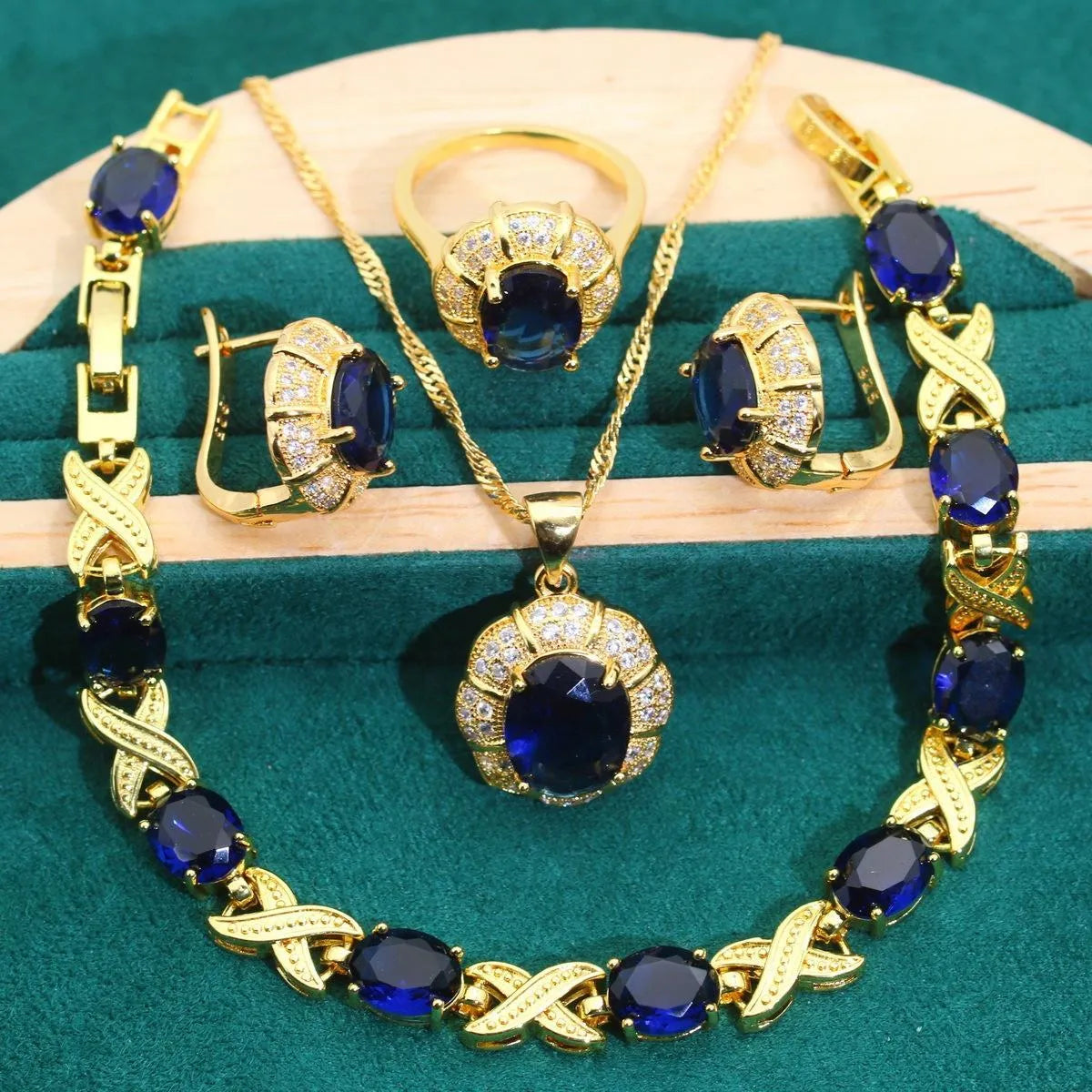 Gold plated jewellery set with blue cubic zirconia stones, showing necklace, earrings, ring, and bracelet.