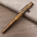Close-up of a solid brass bolt action tactical pen with a press mechanism on a dark surface.