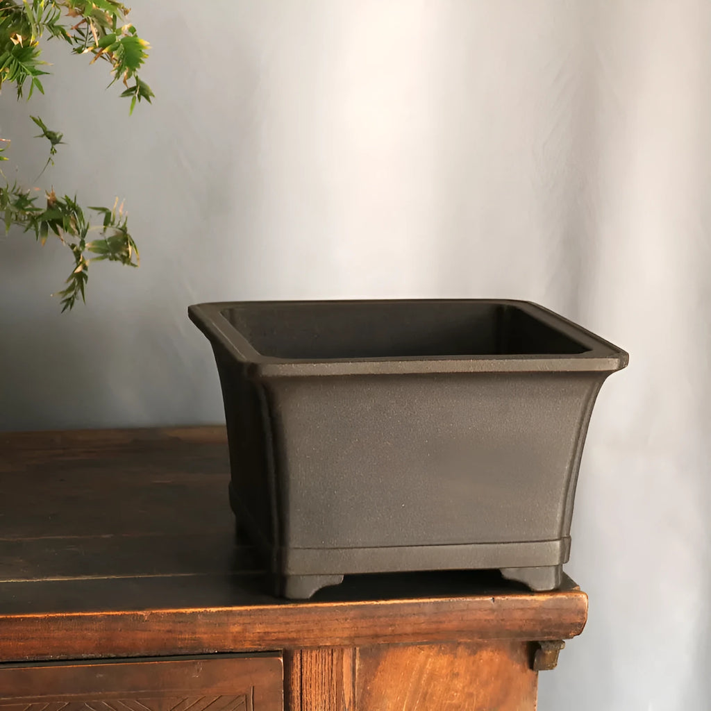 Purple sand square high basin flower pot with black ancient copper clay finish on a wooden table