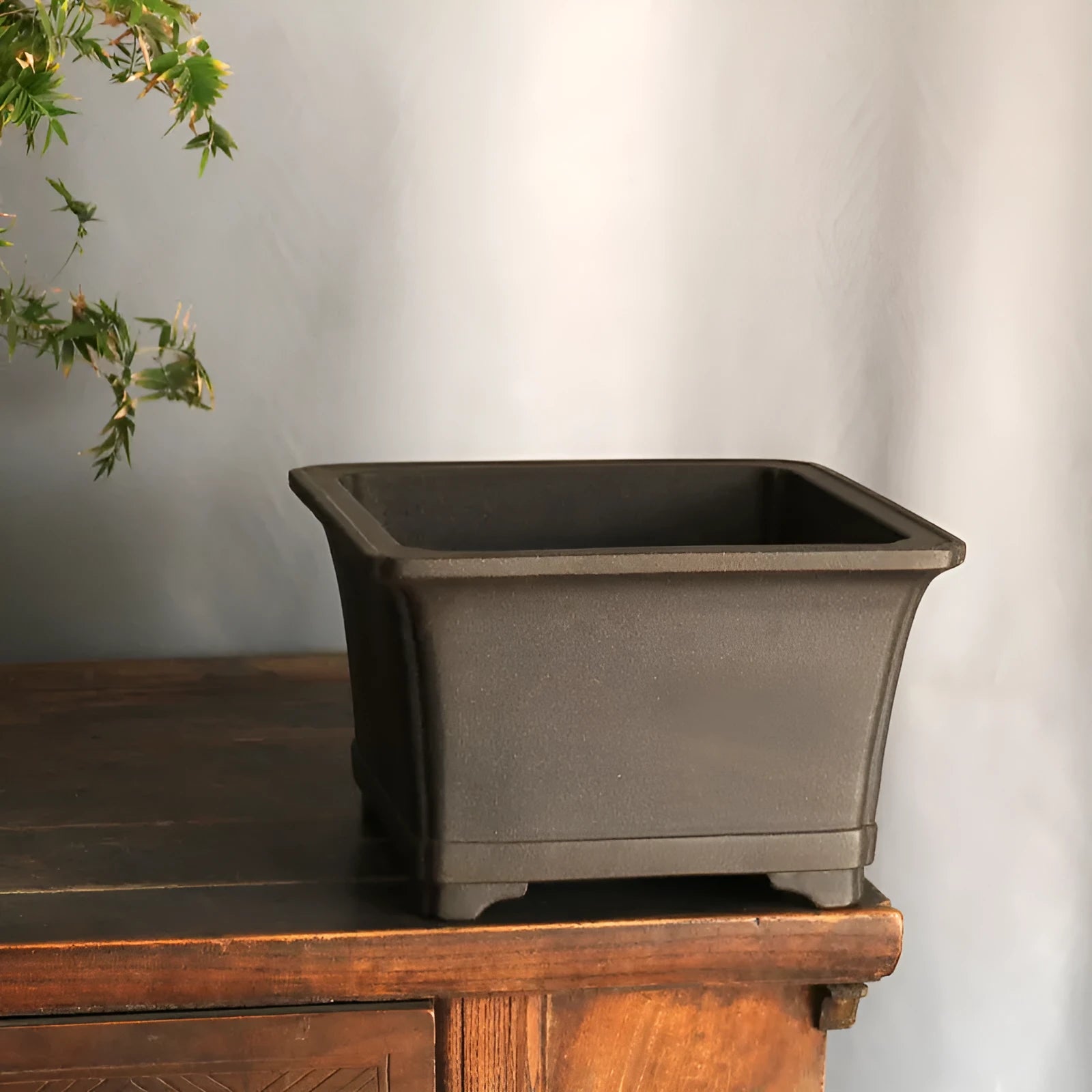 Purple sand square high basin flower pot with black ancient copper clay finish on a wooden table