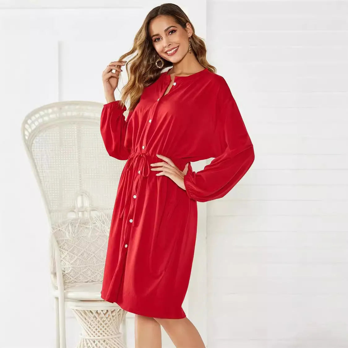 A woman wearing a solid colour A-line midi dress with an elastic waist, an attached belt, and long sleeves.
