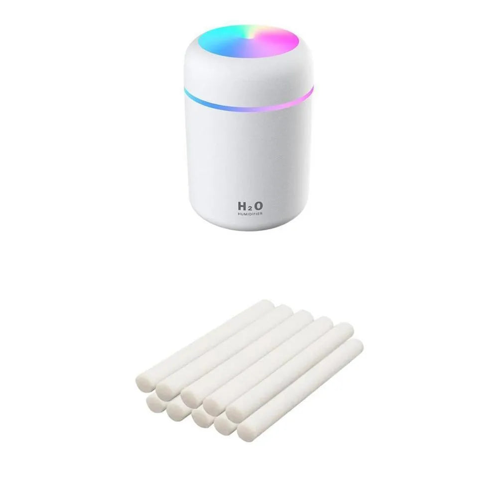 Pink USB desktop humidifier with LED lights and water tank on a wooden desk.