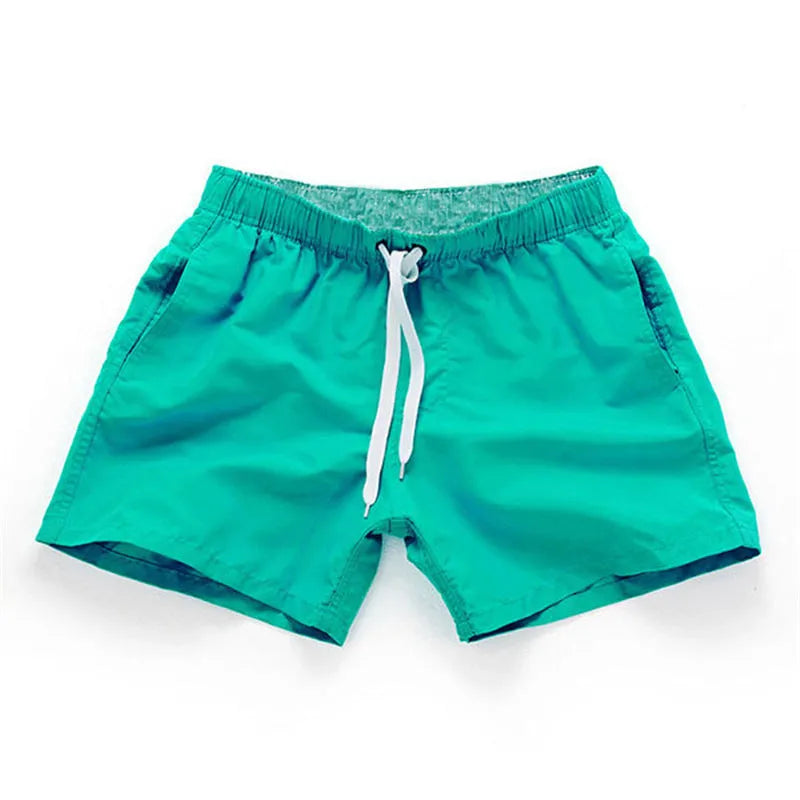 Men's black surf shorts made from polyester fabric with a straight leg opening, shown on a size chart.