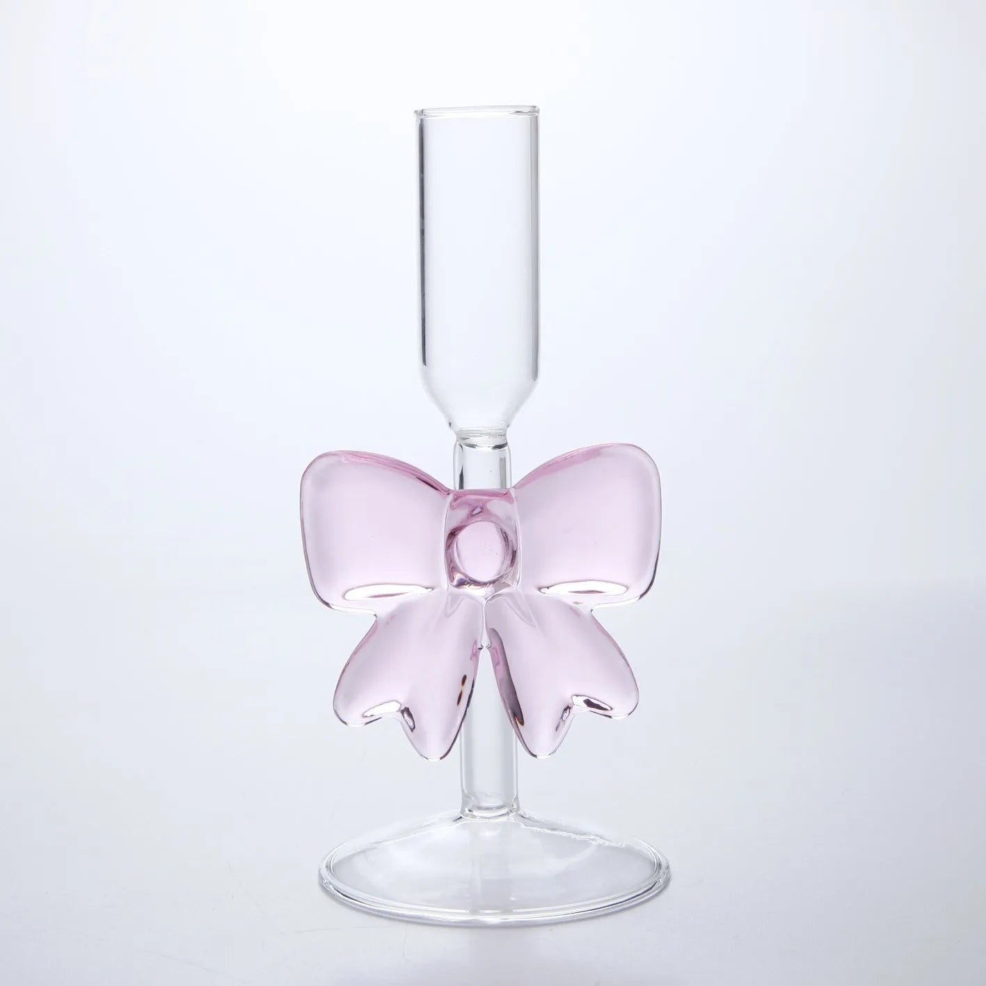 Set of three clear borosilicate glass candlesticks with large bow decorations on a table