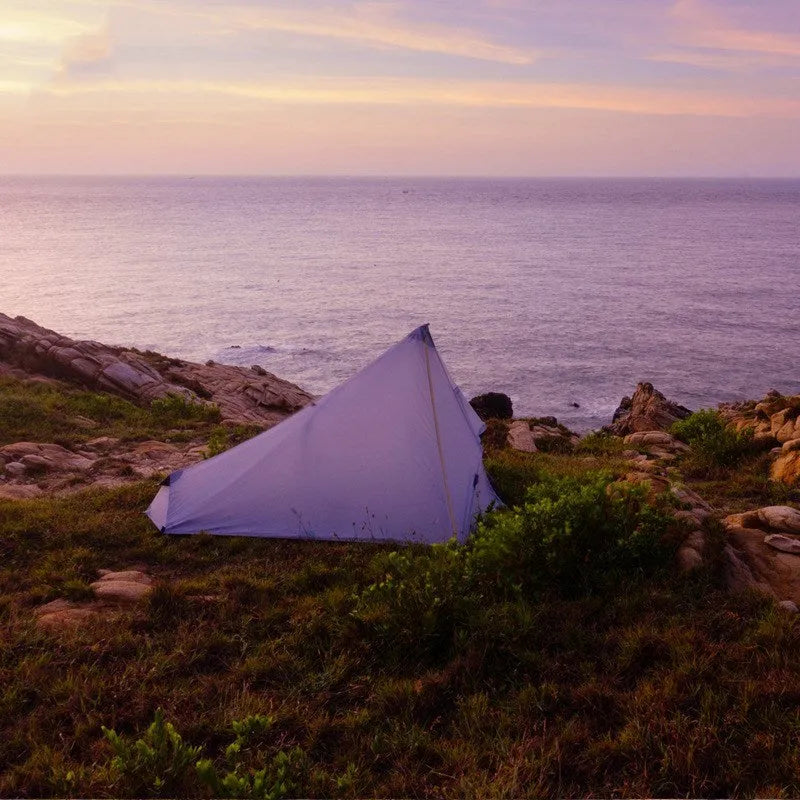 Green silicon coated outdoor camping pyramid tent pitched on grass with aluminium pole and reflective wind ropes
