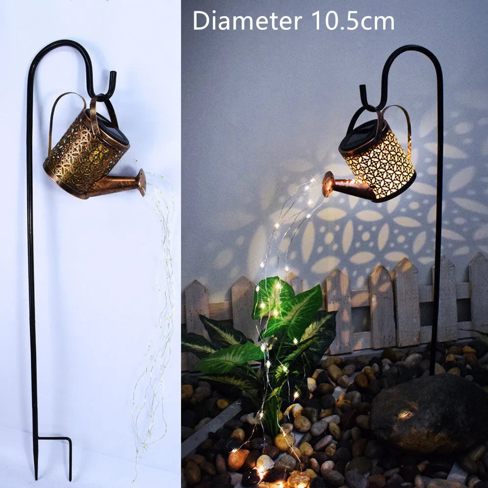Enchanted watering can solar lamp with warm white star-shaped LED lights in a garden setting