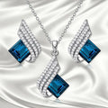 Glass pendant on an alloy cross chain necklace with matching ear studs, in two colour style options.