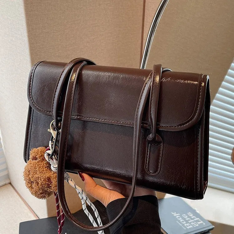 Brown women's Maillard-style PU leather shoulder bag with a double strap and a removable pendant accessory.