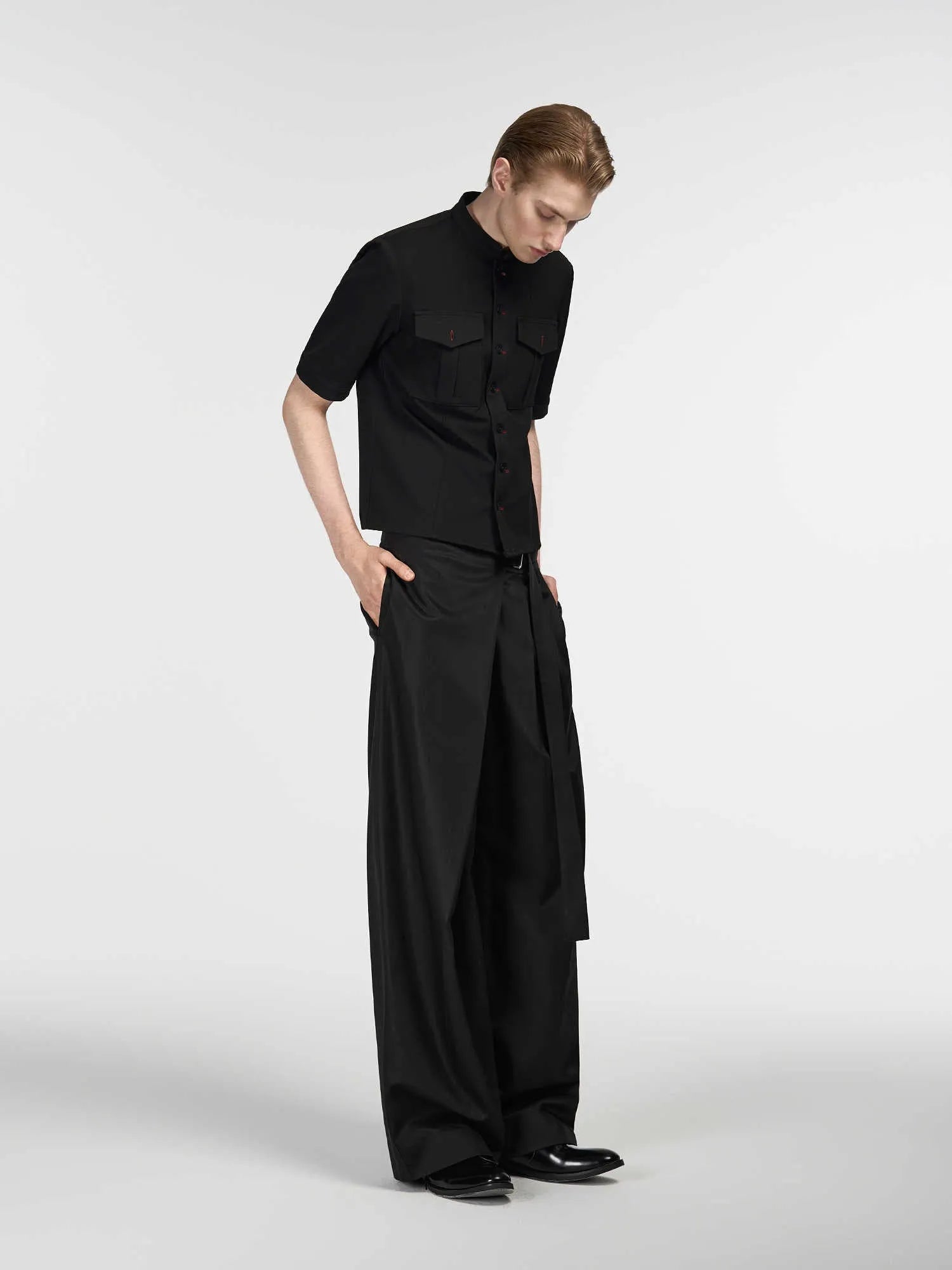 Black straight-leg trousers with a single pleat front and an adjustable waistband, laid flat.
