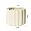 Matte yellow ceramic flower pot with a Roman column design on a table.
