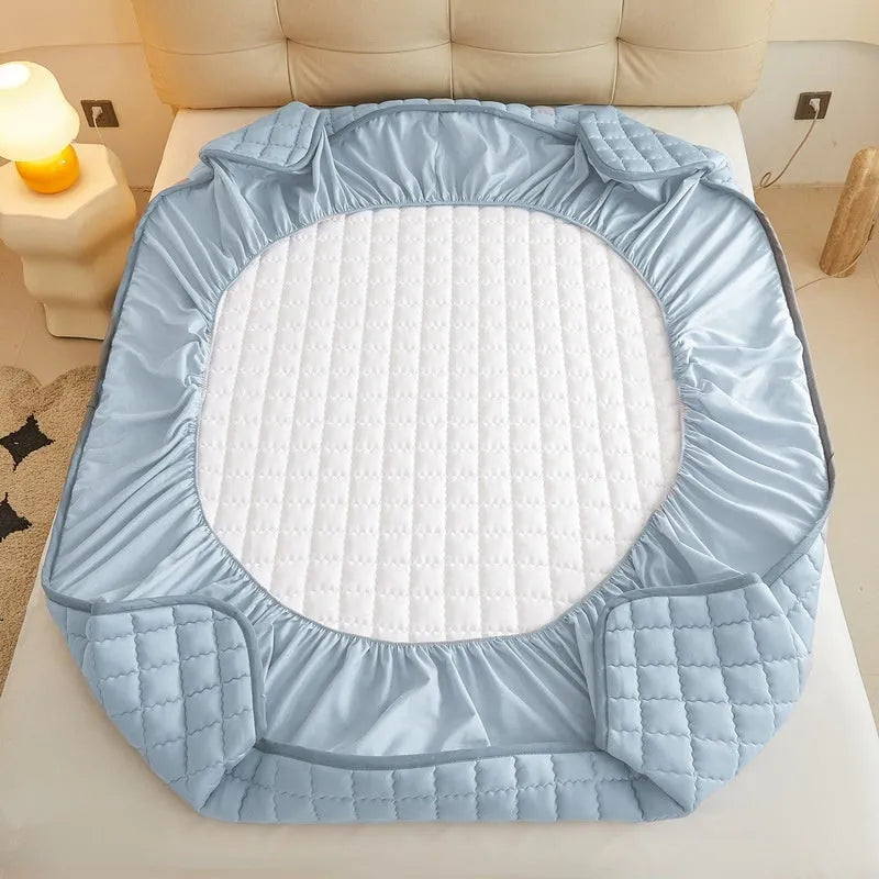 Blue washed cotton fitted sheet with quilted pattern on a bed, showcasing its waterproof protection feature.