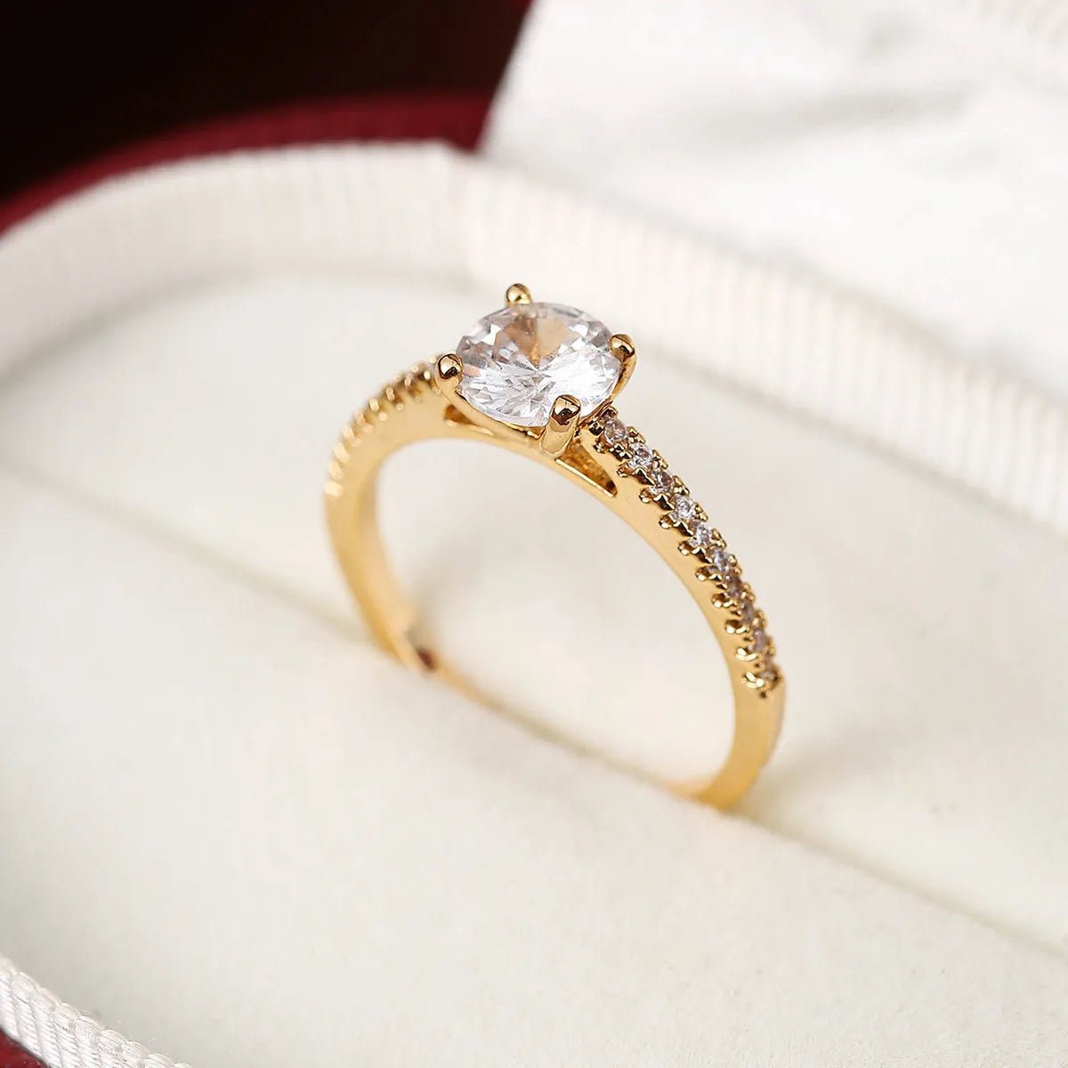Hexagonal geometric copper ring with zircon electroplating in a gold rose red finish on a hand.