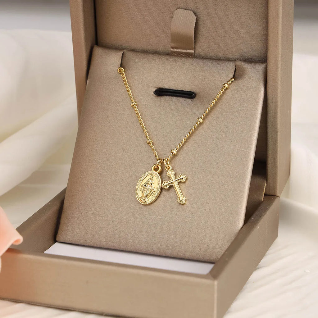 Gold-coloured geometric Virgin Mary and cross pendant necklace on a chain.