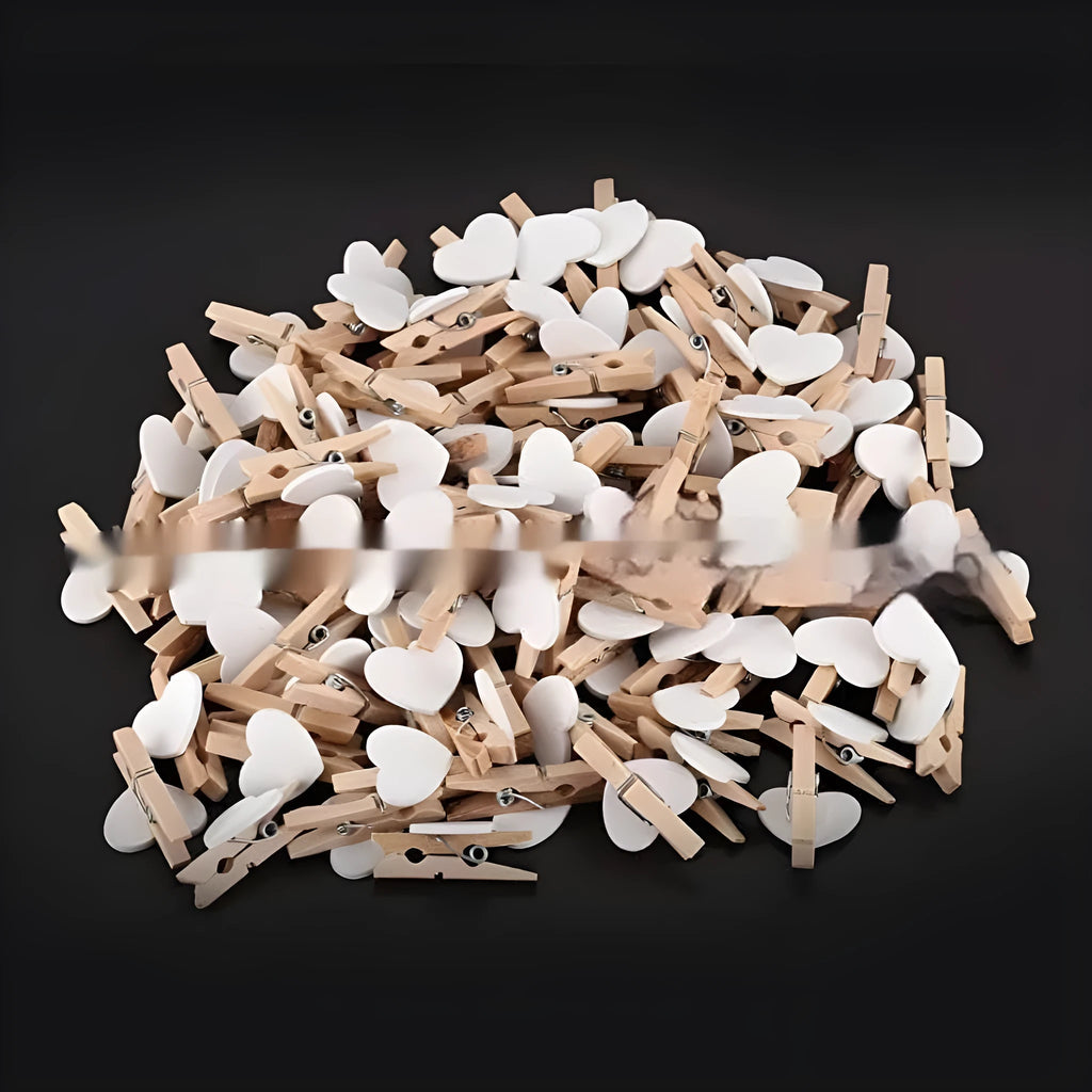 Set of five solid wood heart-shaped clips in different colours on wooden surface