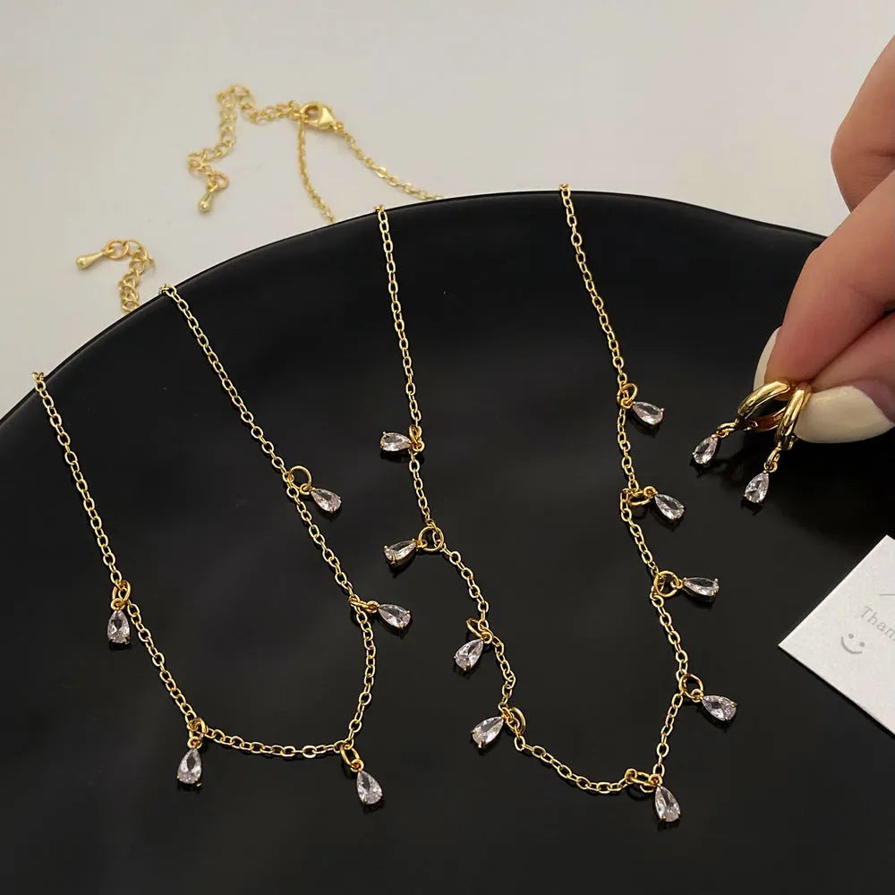 Women's zircon jewellery set showing geometric pendant necklace, matching earrings, and anklet on a white background.