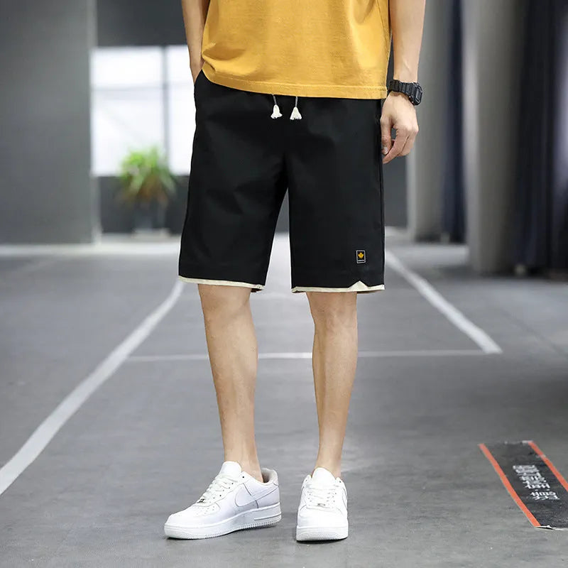 Man modelling loose-fitting straight-leg casual shorts in a solid colour on a beach.