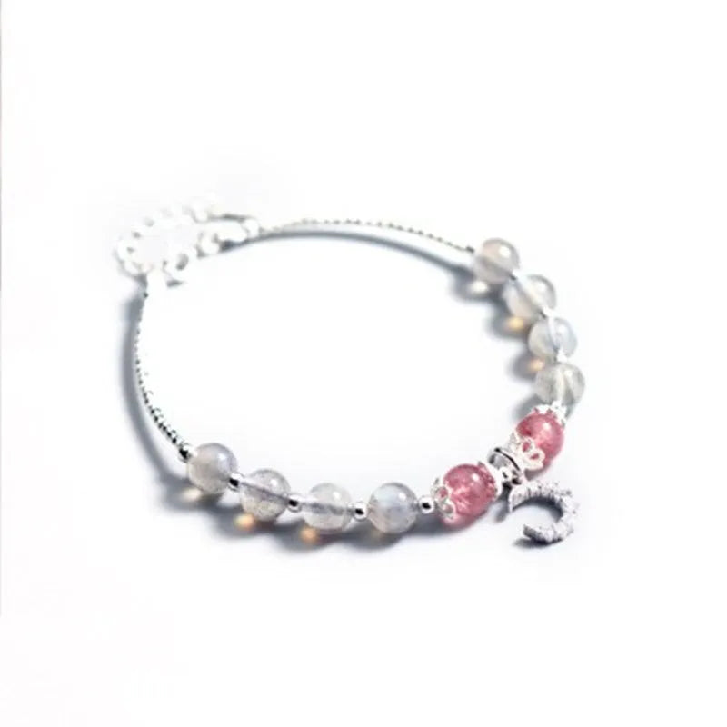 Handmade adjustable moonstone bracelet with crescent moon charm and crystal bead on a white background.