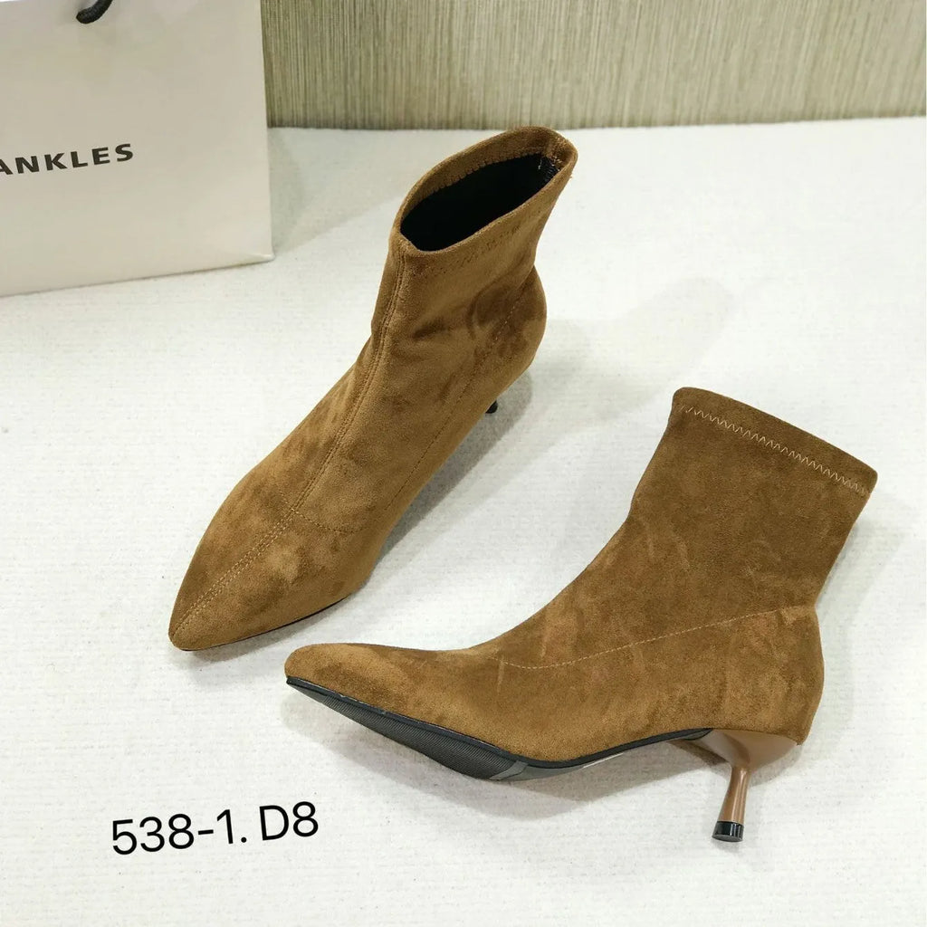 Black pointed toe women's ankle boots with stiletto heels on a neutral background.