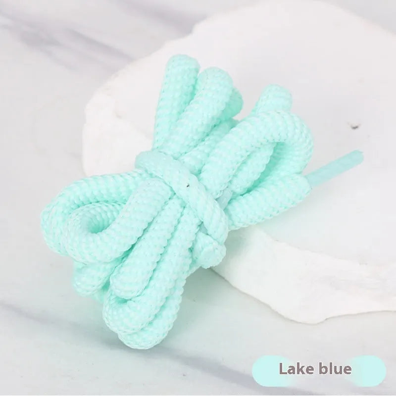 Oval cross-section shoelace adapter rope in various colours, shown next to a trainer and sweatshirt.