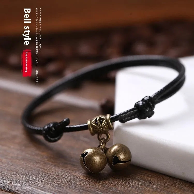 A black nylon rope dog halter collar with a brass bell and adjustable brass buckle on a white background.