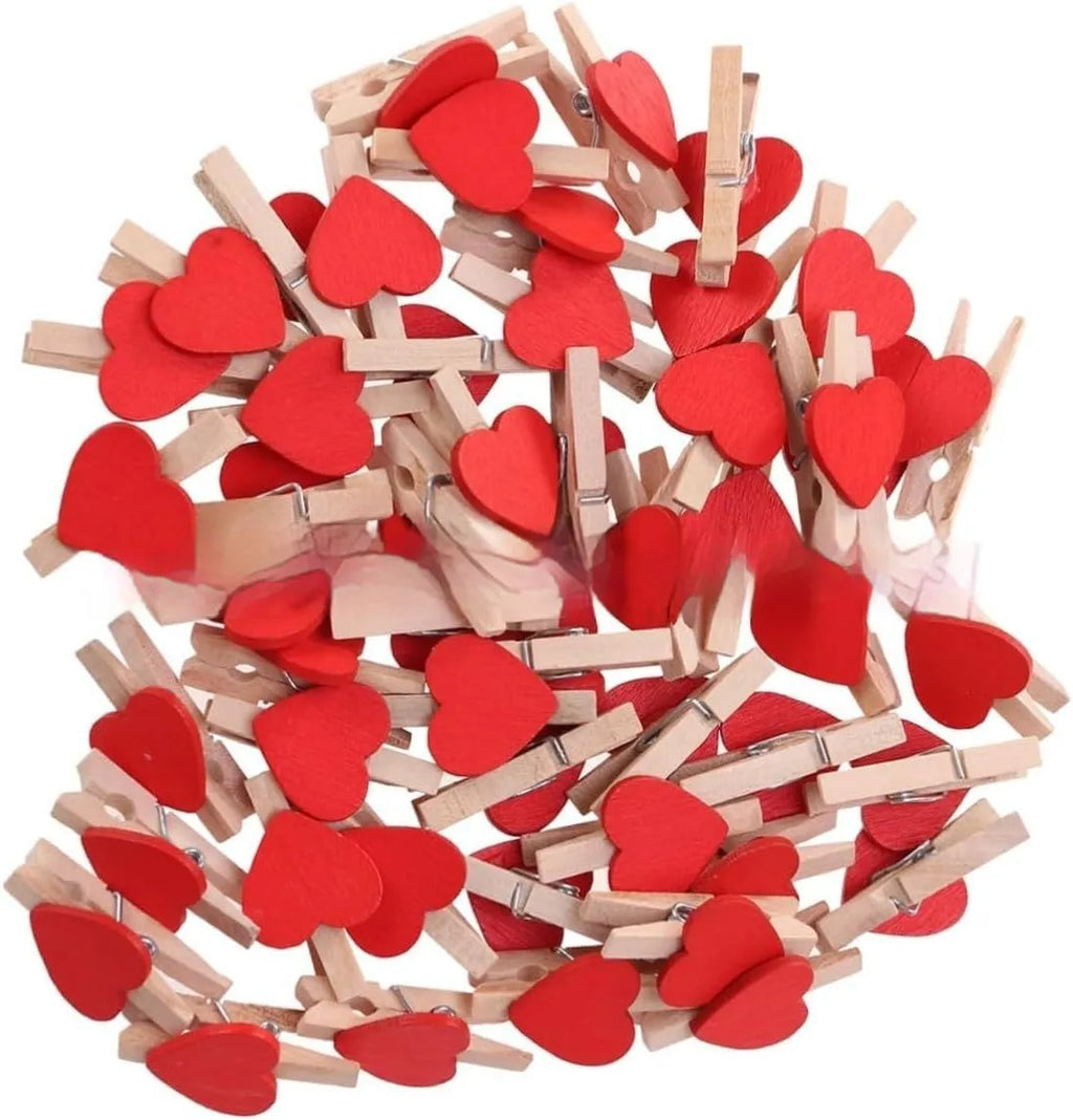 Set of five solid wood heart-shaped clips in different colours on wooden surface