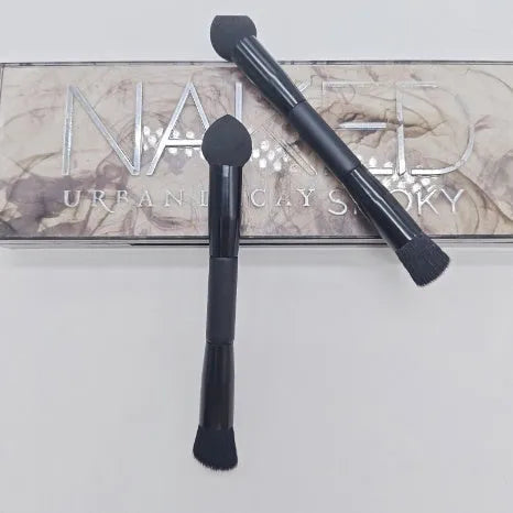 Double-headed black makeup brush with a pointed concealer brush on one end and an angled sponge on the other.