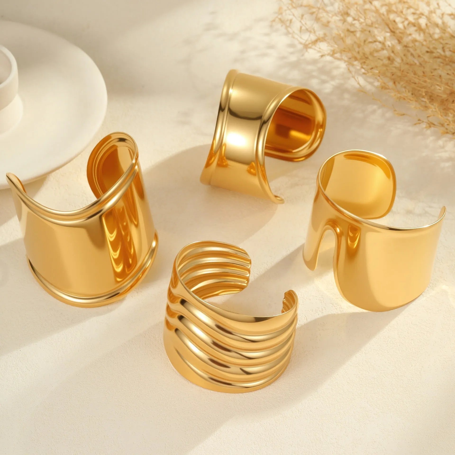 Gold plated wide stainless steel bracelet with a geometric wave shape and a niche opening.