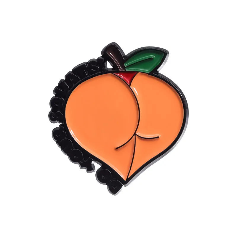 Colourful cartoon fruit and letter design metal brooch on a fabric background.