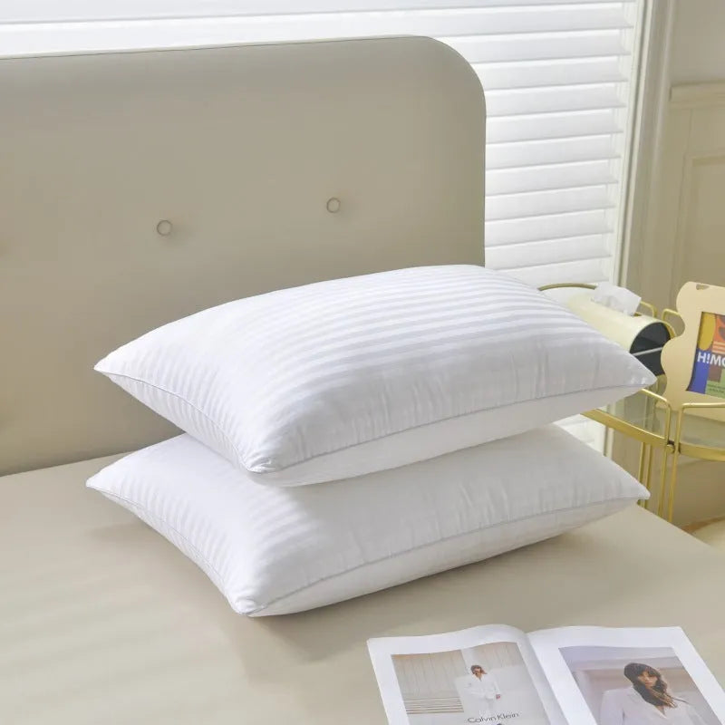 White cotton satin stripe pillow with feather and cotton filler on a bed.