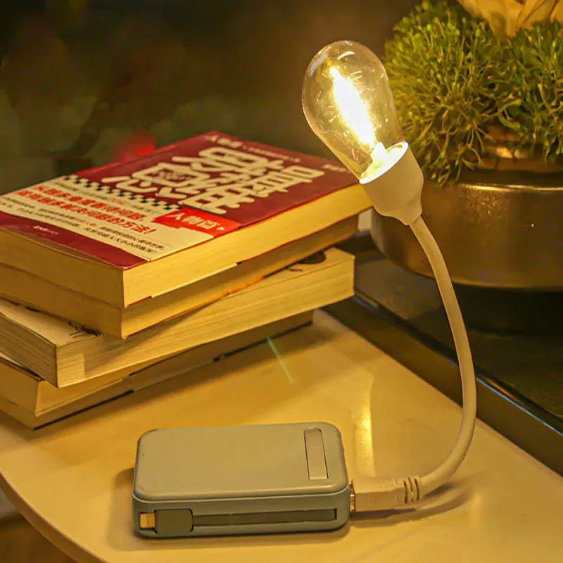 USB rechargeable folding night light with a glowing tungsten filament bulb on a table.