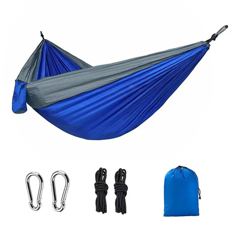 Blue ripstop nylon outdoor hammock with suspension ropes hung between trees