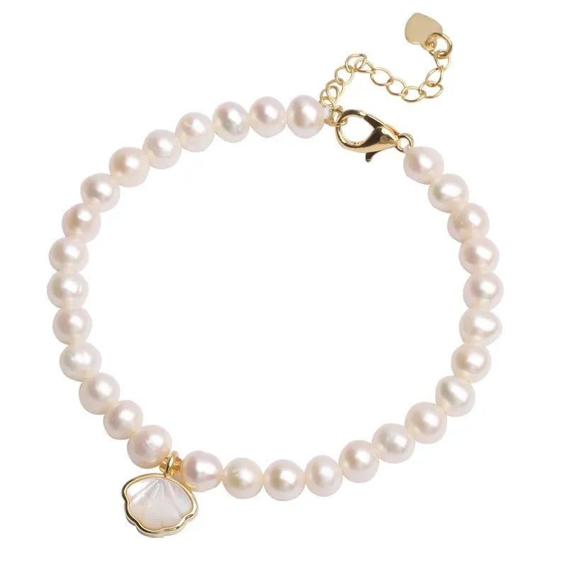 Women's freshwater pearl bracelet with fan-shaped charm on wrist, showing elastic and chain fastening options.