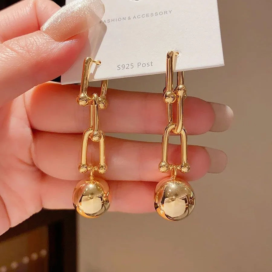 Gold long fringe earrings on display showing geometric line design and electroplated metal finish