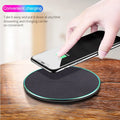 Black Qi wireless fast charging pad for iPhone 11 on a wooden surface.