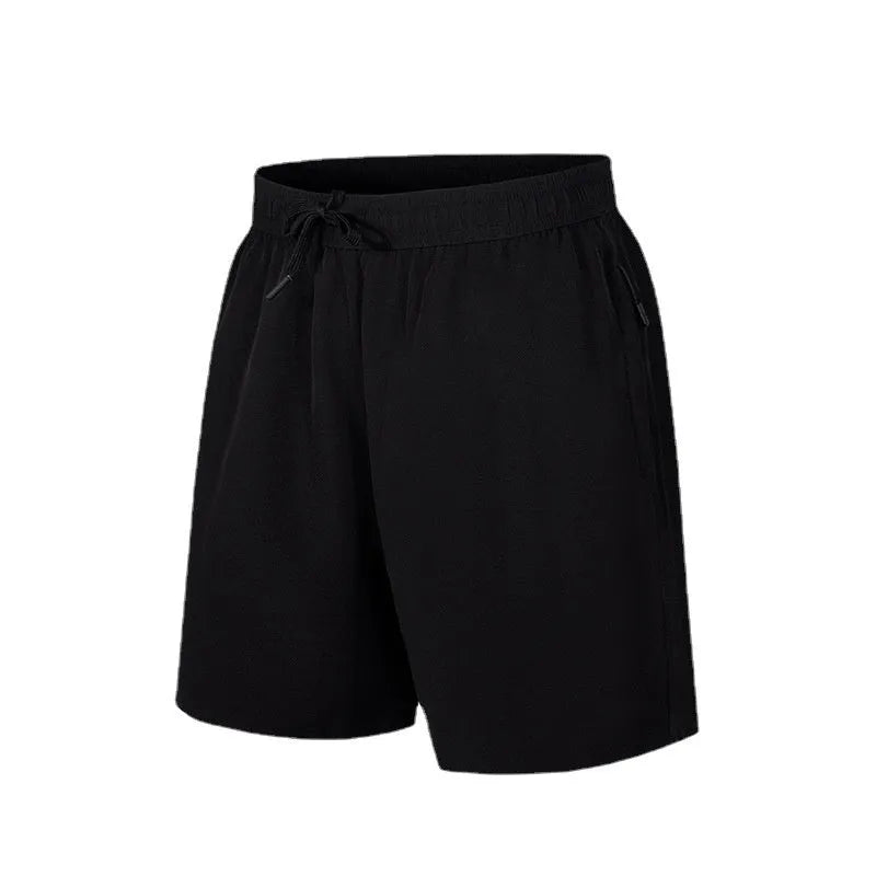 Man wearing loose-fit black quick-drying polyester beach shorts with a micro-elastic waistband.