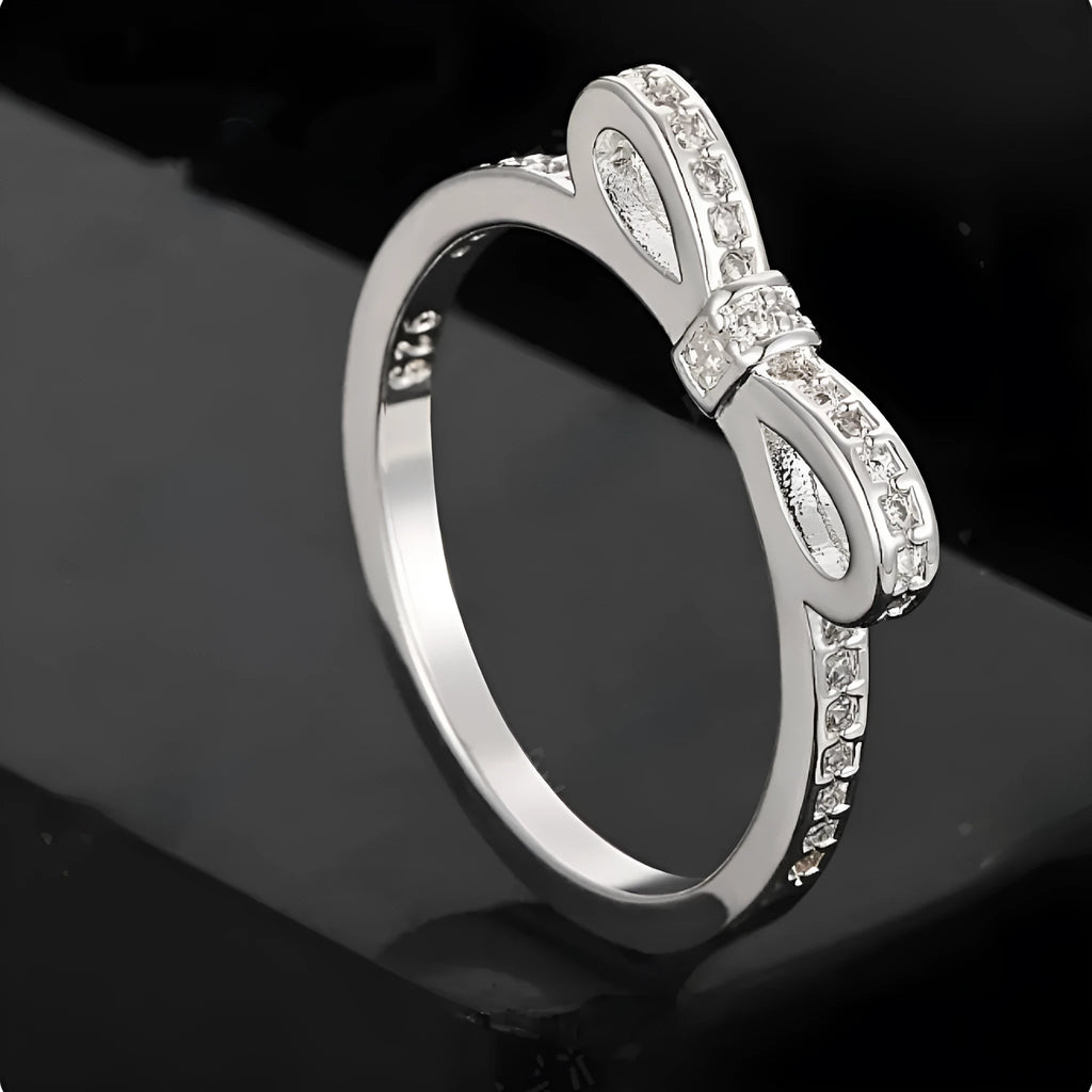 Silver bow-shaped ring with crystal rhinestones on finger