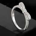 Silver bow-shaped ring with crystal rhinestones on finger