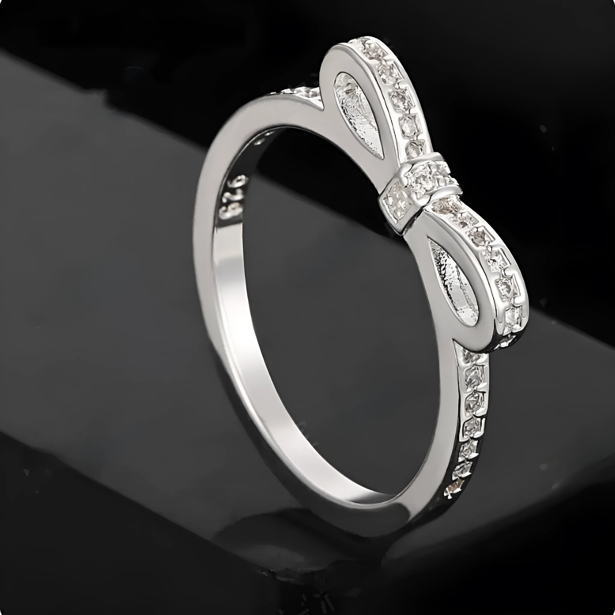 Silver bow-shaped ring with crystal rhinestones on finger