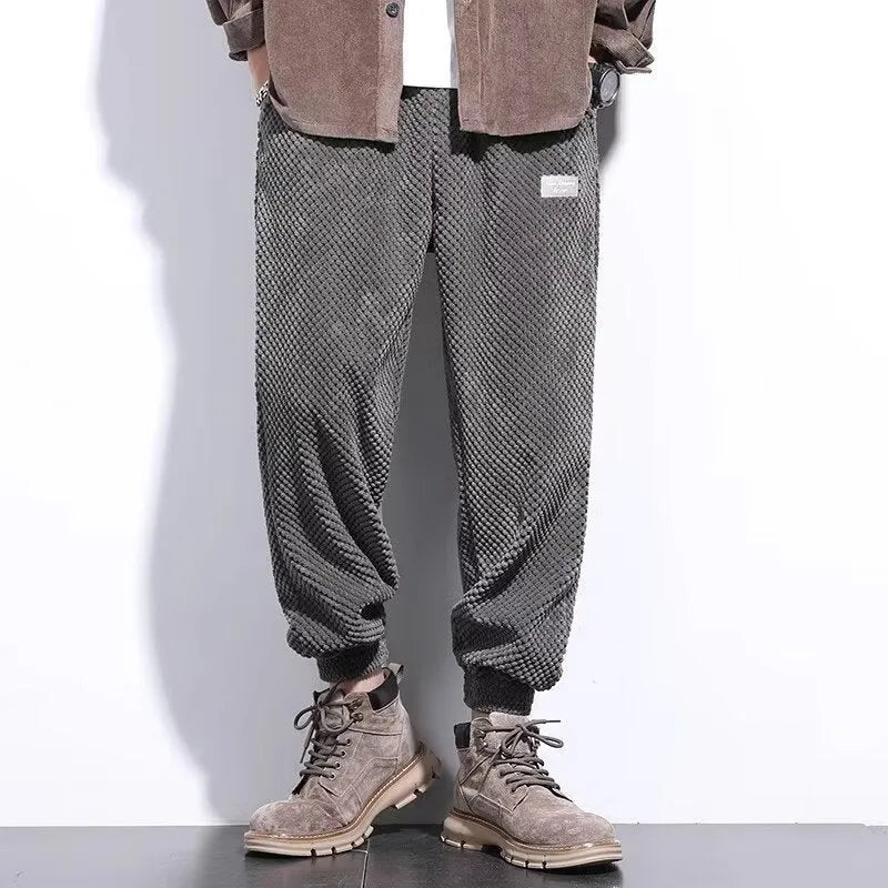 Men's grey ankle-tied straight leg sweatpants laid flat on a surface.