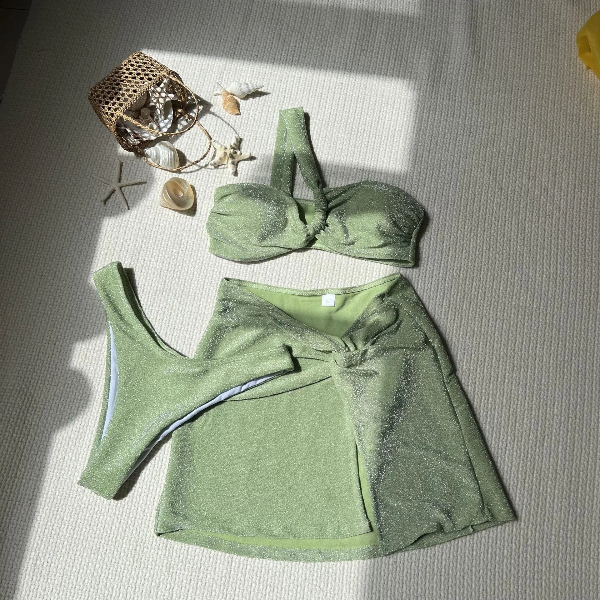Light green one-shoulder tube top three piece swimsuit set for women with matching briefs and skirt.