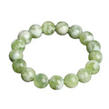 Green milk-in-water Xiuyan jade polished bracelet with geometric beads on a neutral background