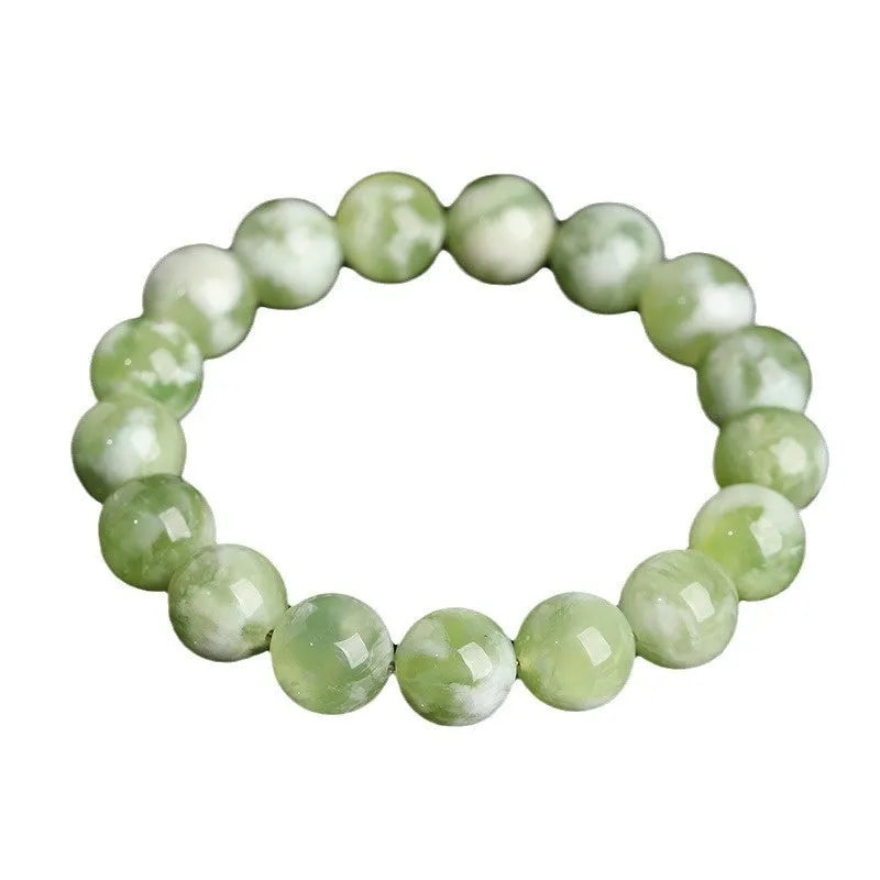 Green milk-in-water Xiuyan jade polished bracelet with geometric beads on a neutral background
