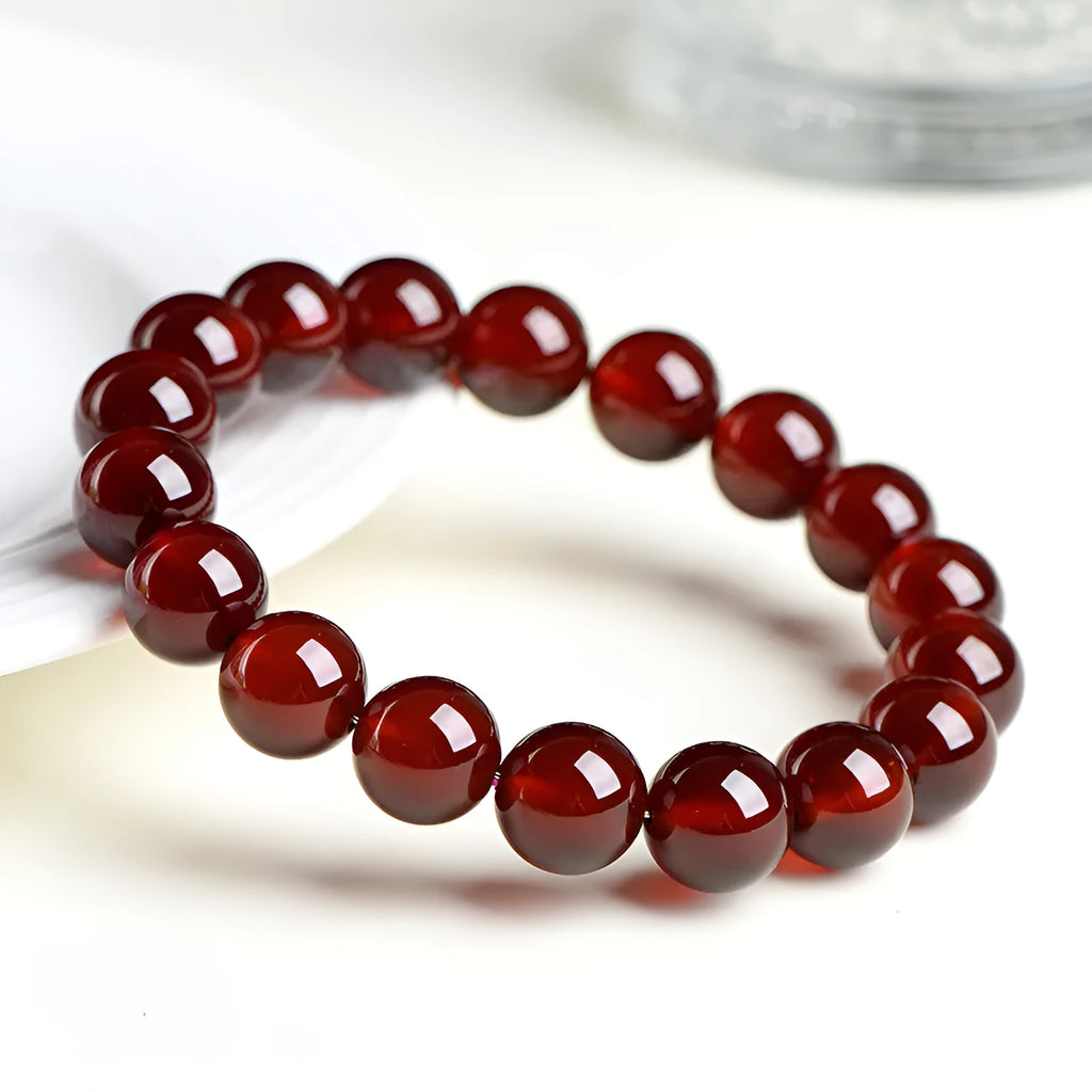 Natural orange red garnet ball bracelet in retro unisex style on wrist, showing crystal links and ruyi design details.