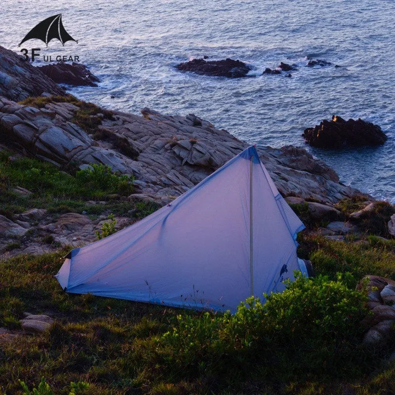 Green silicon coated outdoor camping pyramid tent pitched on grass with aluminium pole and reflective wind ropes