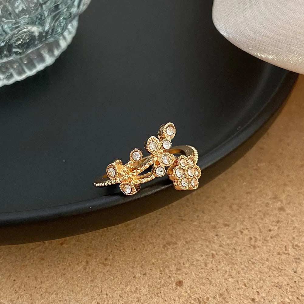 Women's open ring with floral leaf design in gold tone on white background