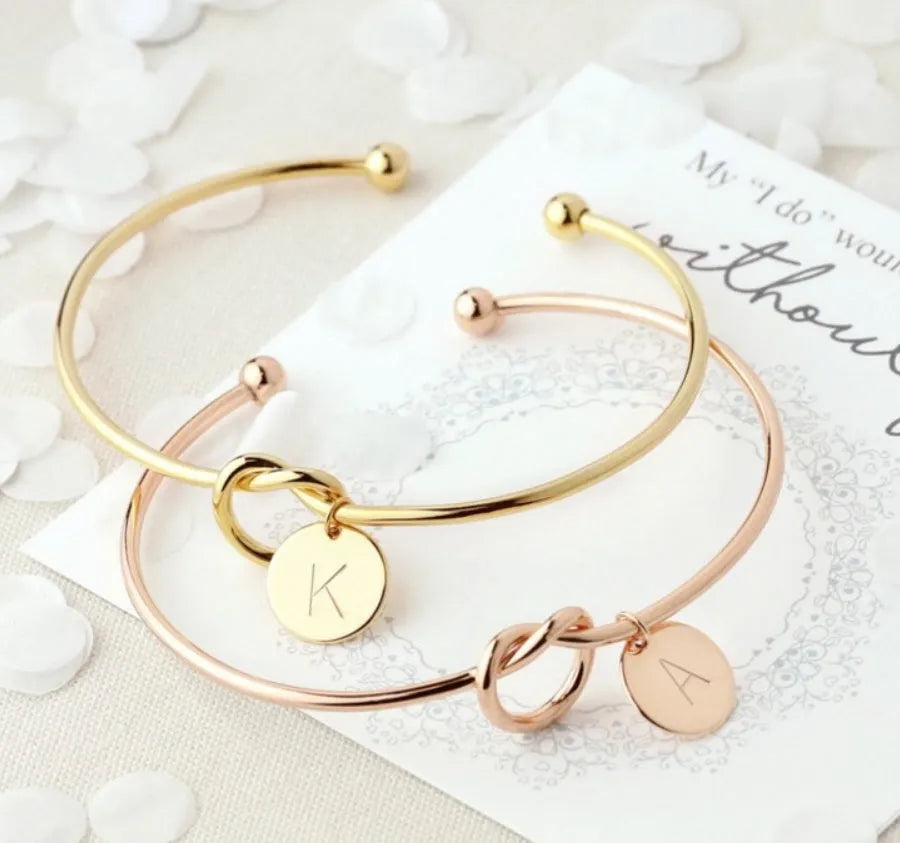 Personalised initial heart knot bracelet in gold finish with custom letter on a white background