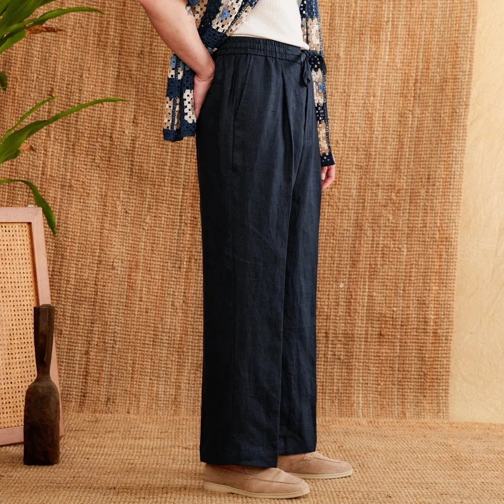 A pair of loose-fit, high-waisted linen trousers in a neutral colour with an elasticated waistband and straight legs.